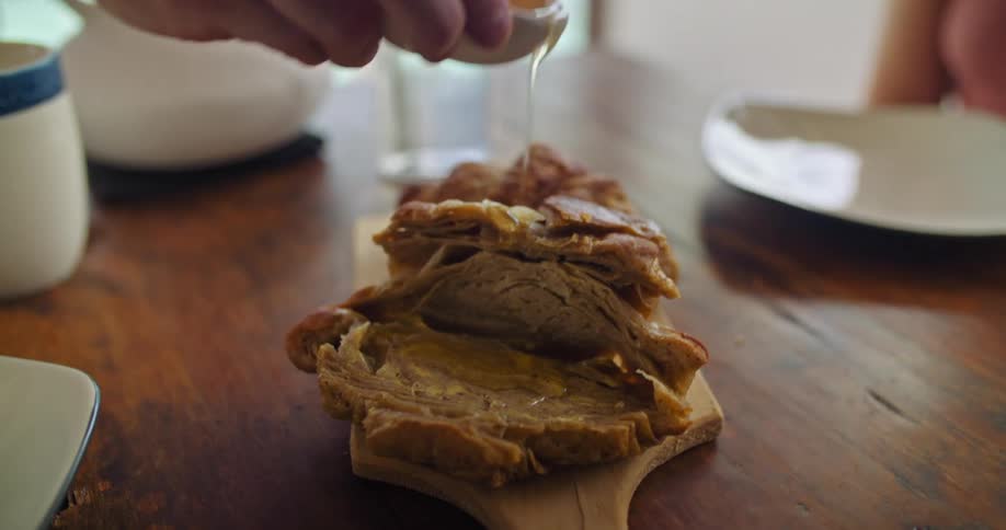 A woman at home pours syrup on some pastries