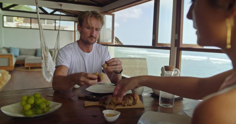 Couple eating and sharing seafood on a tropical beachfront apartment at daytime