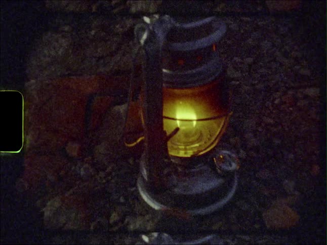 Close up of a vintage gas camping lamp on the forest ground caught on vintage film