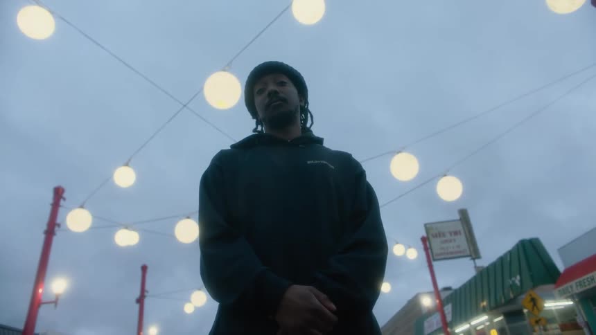 A man standing outside a strip mall of stores under hanging lanterns