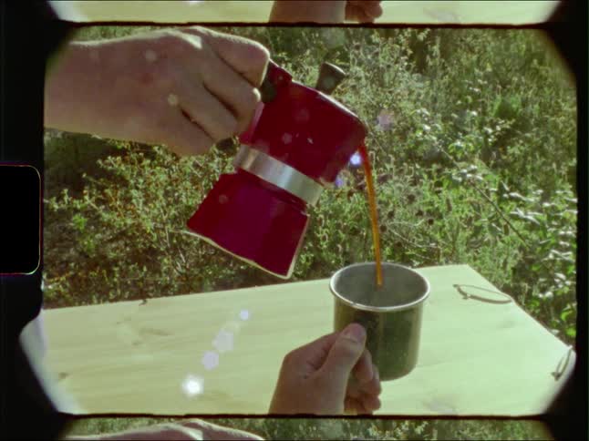 A person pouring a cup of coffee for someone else