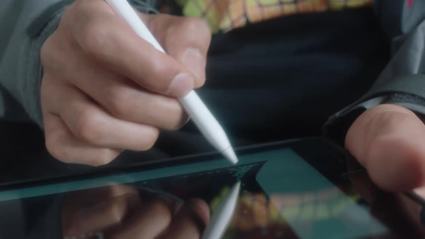 Someone is using a marker to write on the reflective surface of a flat object they are holding