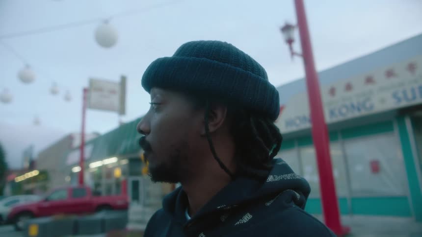 A man stands in front of multiple shops looking at someone in the distance