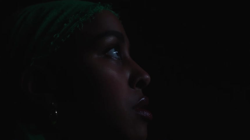 A woman sitting in a room watching a screen
