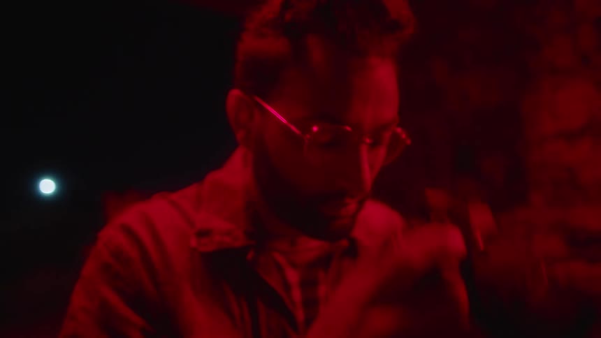Young man takes pictures outdoors with a camera at night under a red light