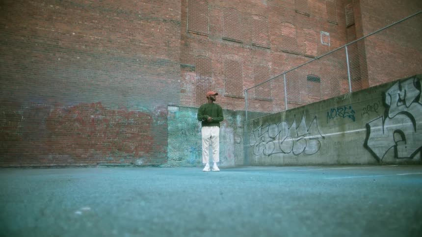 A man stands in front of a large building in a vast desolate area outdoors
