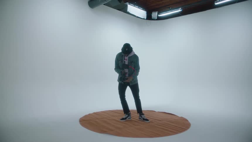 A man stands and takes a photograph in a studio