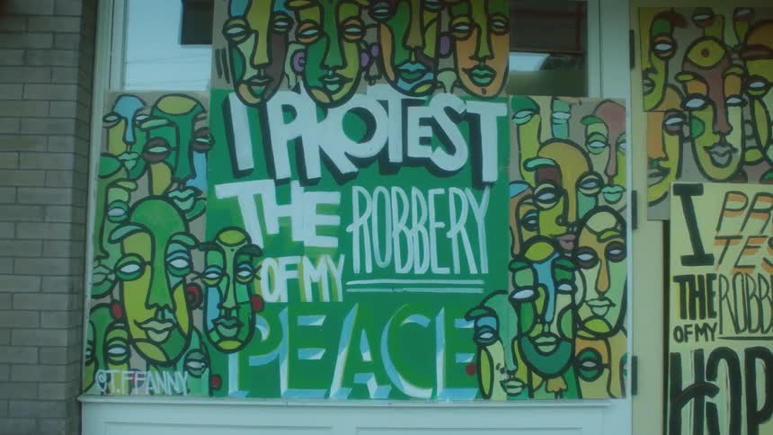 Artful protest signs posted on windows protesting the robbery of peace and hope