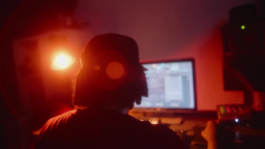 A man works on his computer in a dim room