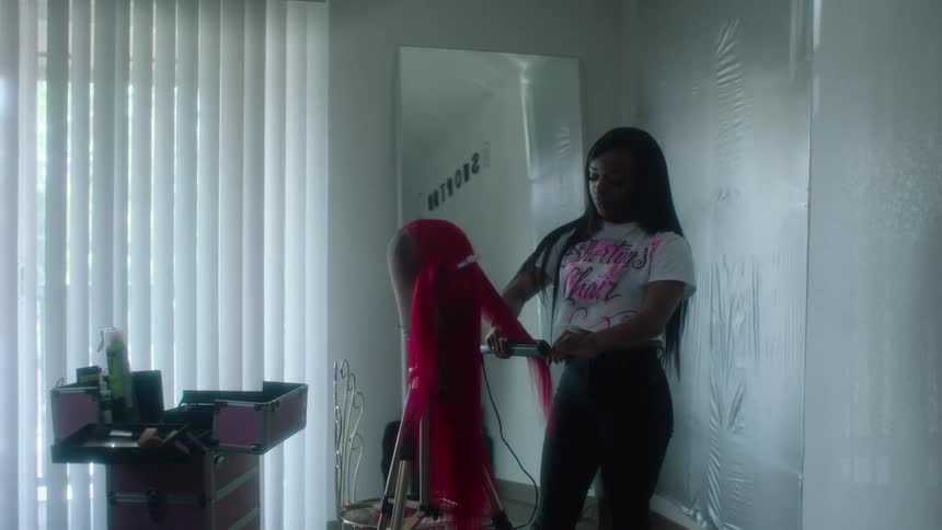A woman straightening hair on a wig