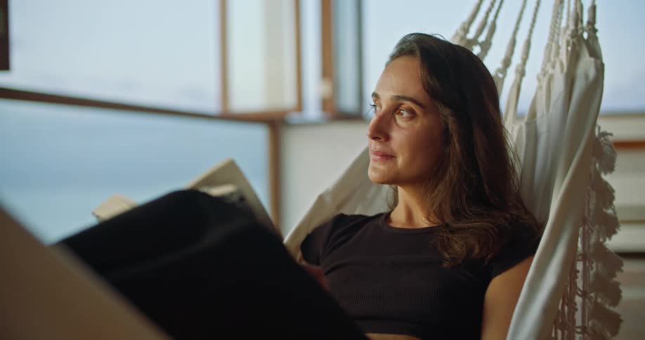 Woman reading a book relaxing on a hammock on a beachfront apartment