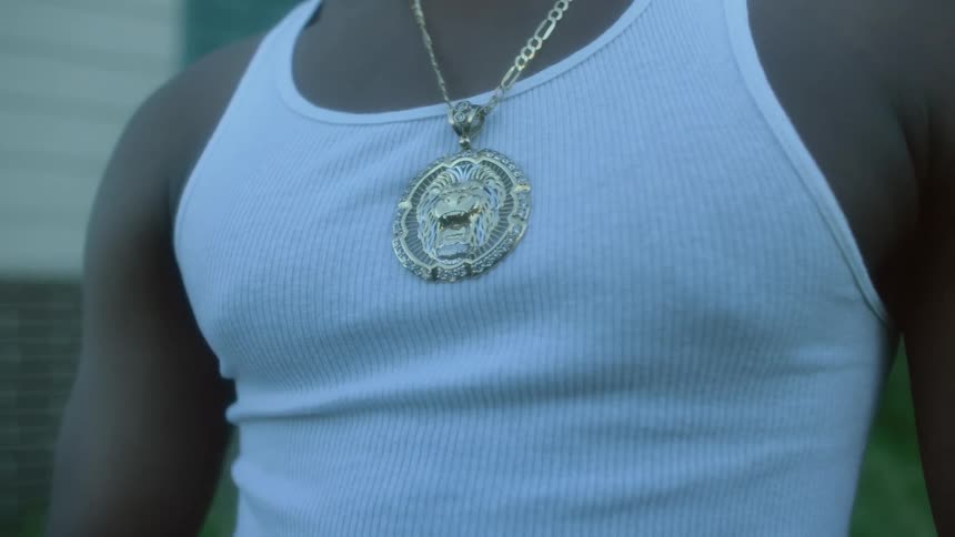 Man stands outdoors near home wearing an elaborate gold medallion