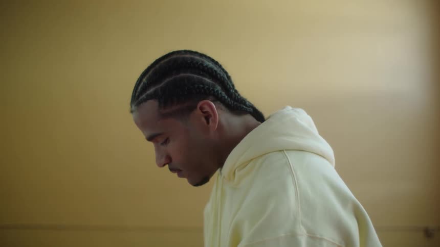 Man wearing pale yellow hoodie bobs his head while concentrating