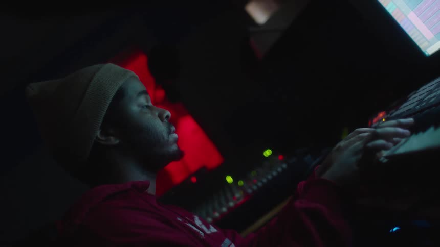 A man looks at a computer screen as he plays music on an electric keyboard