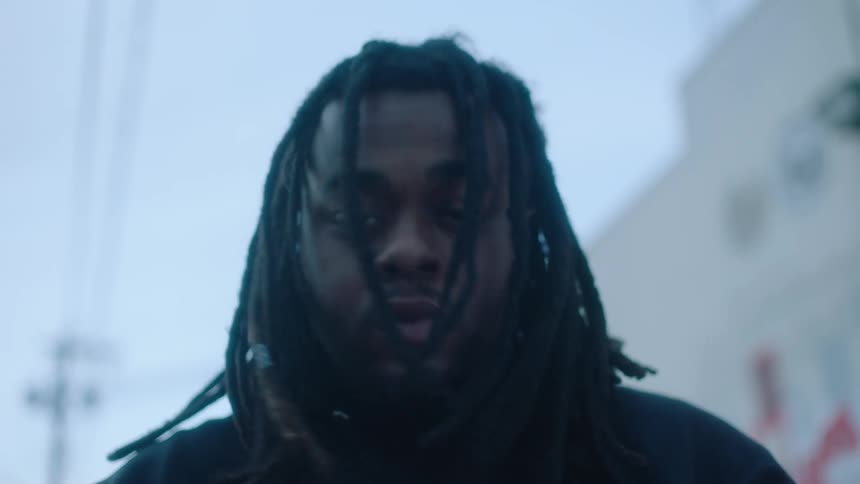 Man with dreadlocks and black top shakes his head