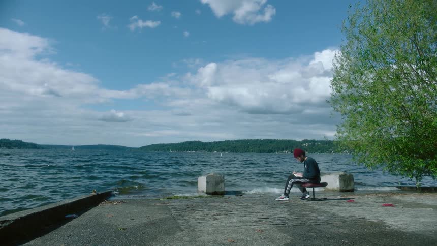 A man sits on the shore reading a book