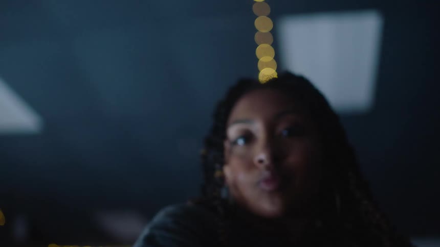 A teenage girl dances inside under lights