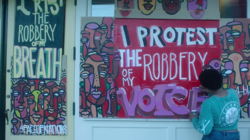 A woman is painting graffiti on the building