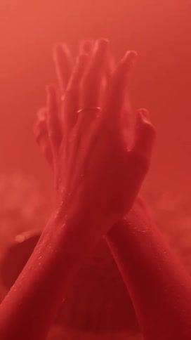 A womans hands and arms are moving in a room filled with red light