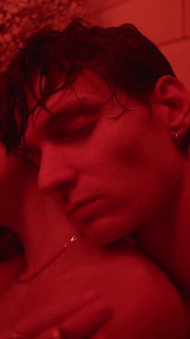 A man has his eyes closed as a red light slowly flashes in the room