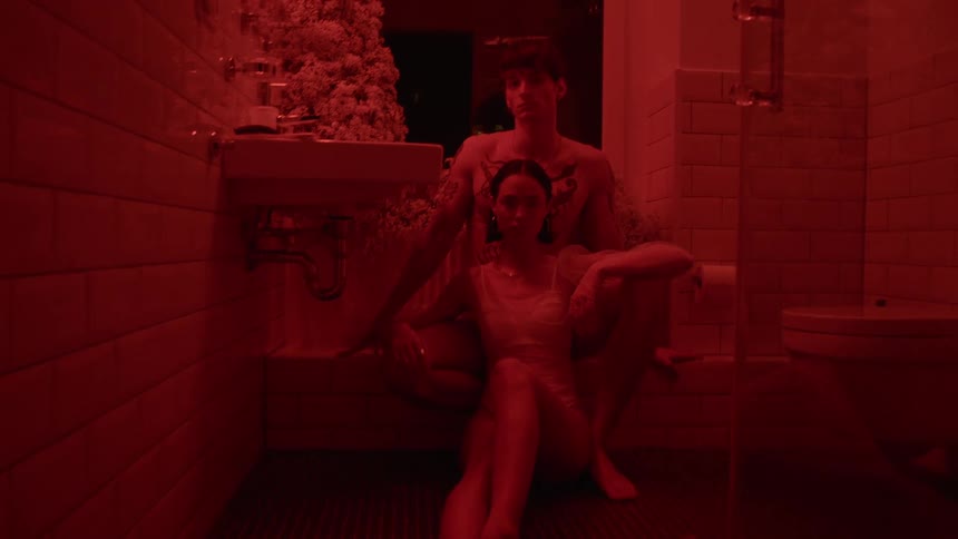 Couple pose sitting in front of window in bathroom lit by red light