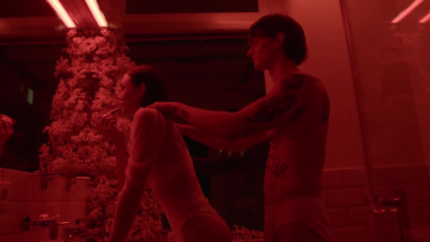 A man massages his girlfriends shoulders while she applies lipstick in the bathroom