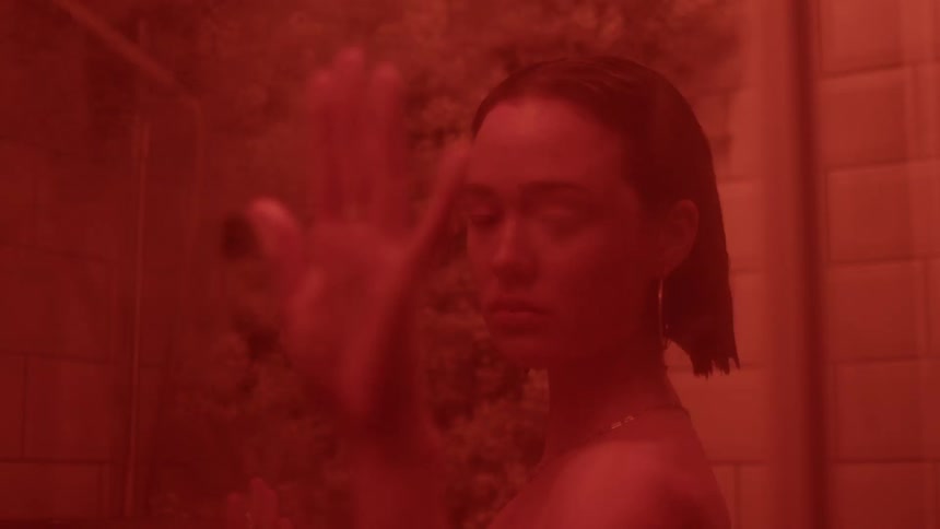 A woman presses her hand against a glass shower door