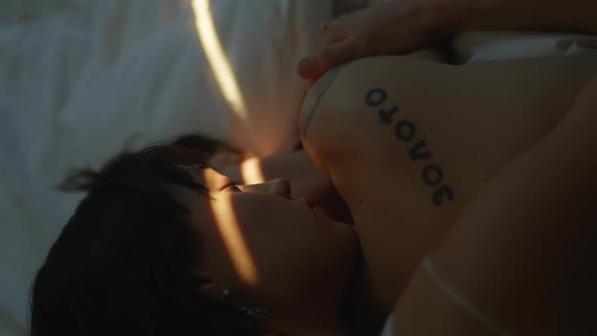 A woman sleeping with her arm over another person opens her eyes