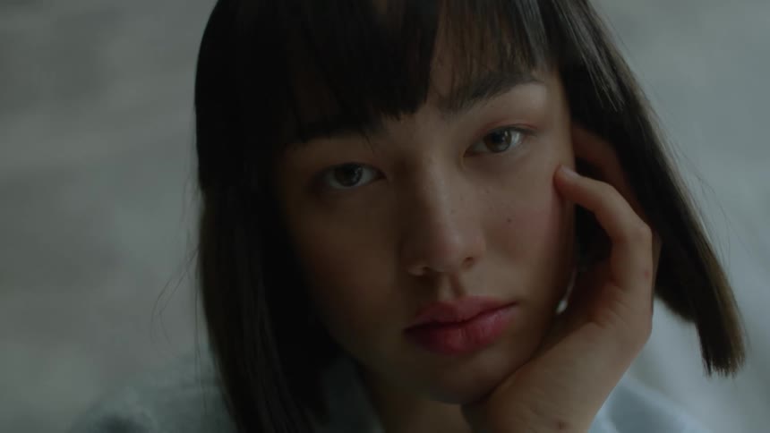 A woman is resting her chin on her hand and looking ahead