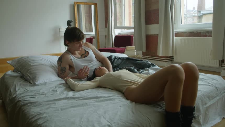 A woman looks up at her partner as they lie in bed