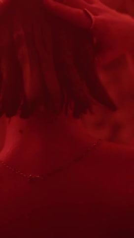Person standing in room lit by red light strokes hair