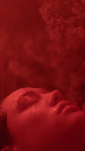 A woman leans her head back as water runs over her face in the shower