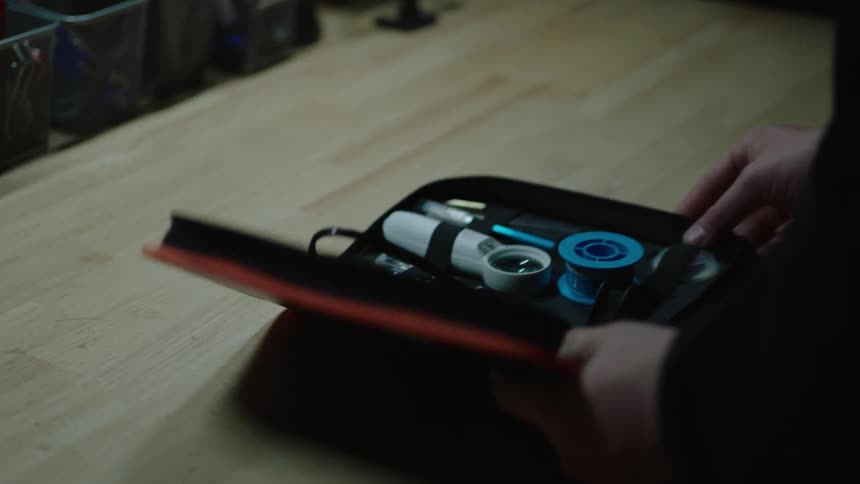 A person opens a first aid kit over a table