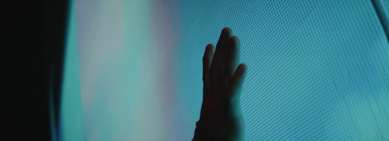 A man presses his hand against a large screen playing static