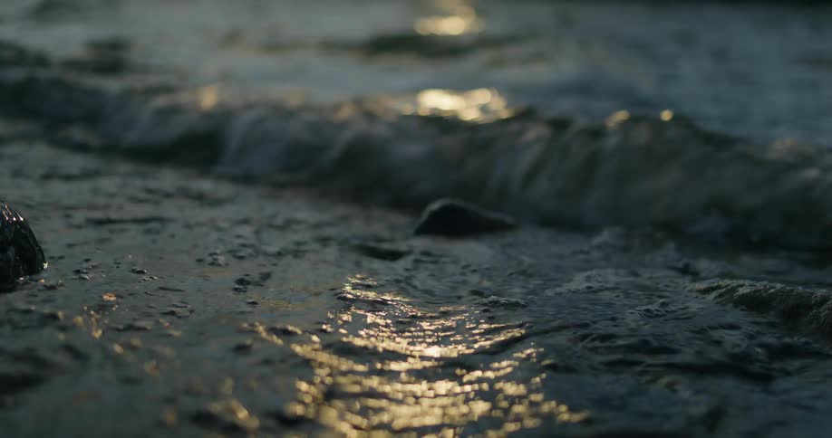 Small waves passing over rocks with sunlight shimmering on the surface