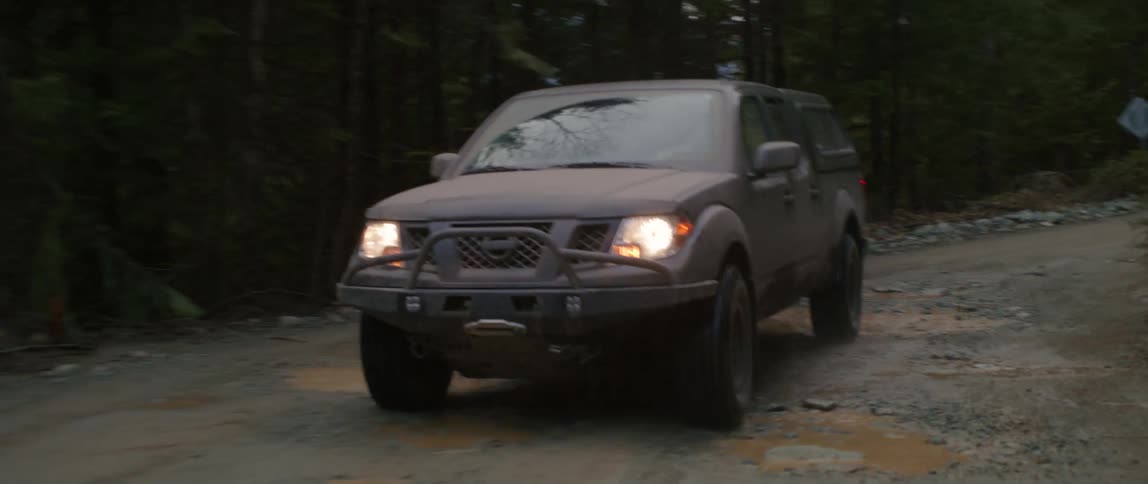 A truck traveling on a dirt road splashes through potholes