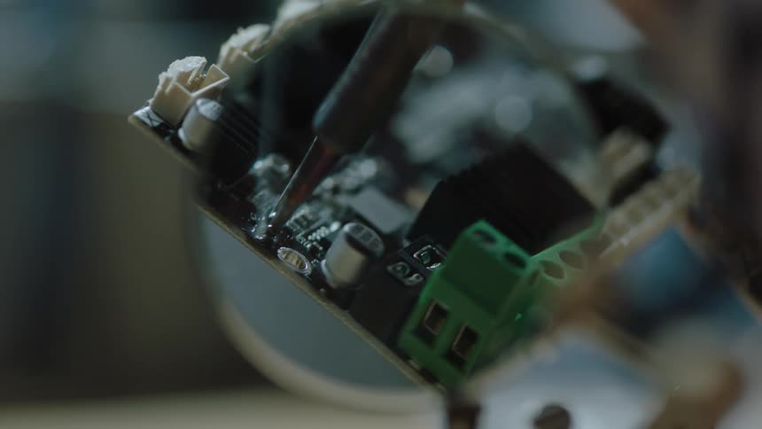 Smoke rises from a soldering iron being used to repair a circuit board