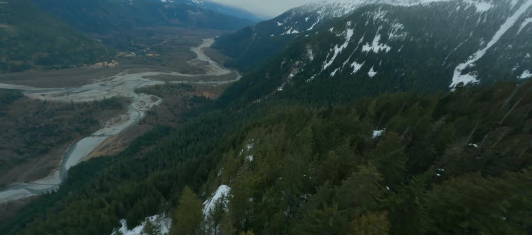 A dusting of snow covers trees along the sides of a mountain range