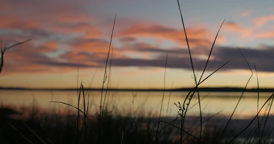 The sun is setting in the horizon near a river