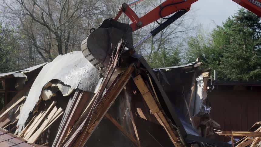 An excavator moving debris from a demolished building