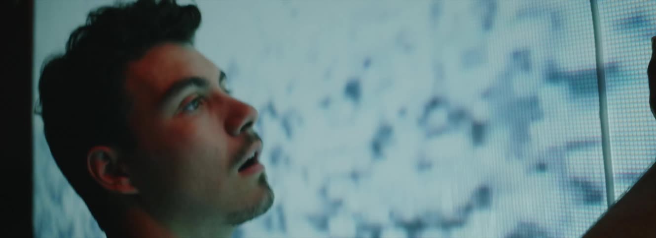 A man stands in a state of stupor with his face a few inches away from a large screen