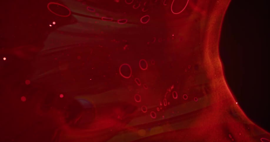 Bubbles move in an organic red substance and holes grow as it breaks apart with orbs floating in the ether