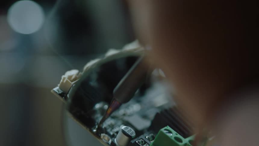 Smoke rises as person solders on circuit board