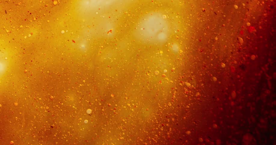 Bubbles move in a red and orange organic substance as darker red moves over the orange