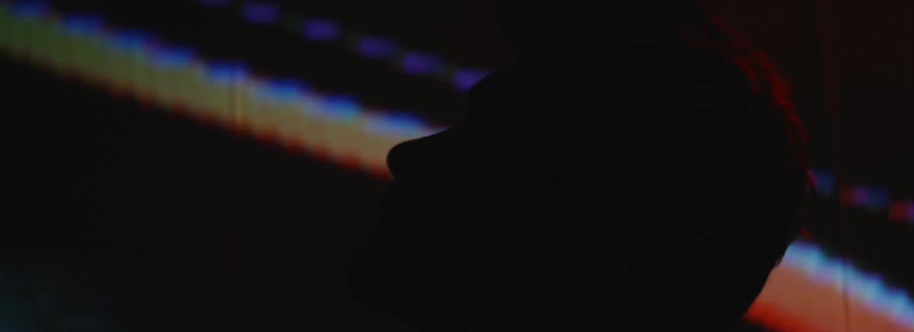 A man in front of a television with a fuzzy screen lifts his head and looks above him