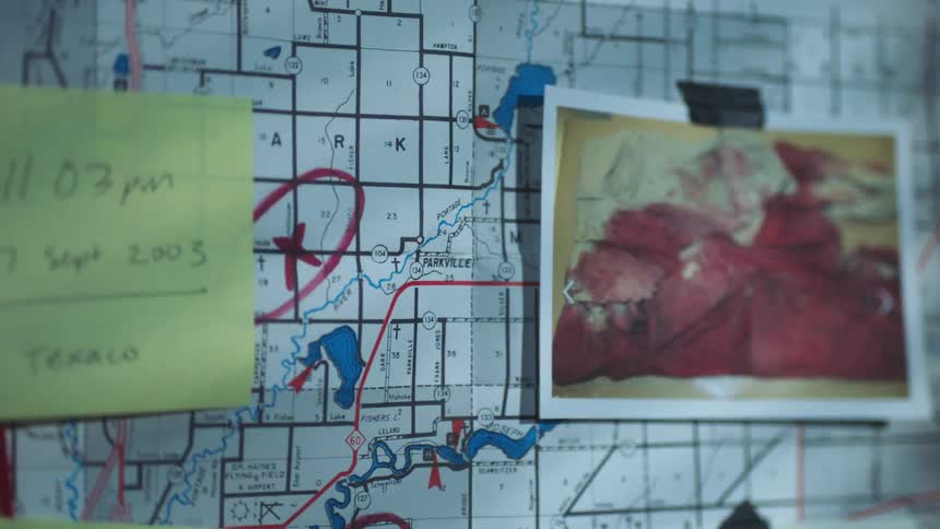 A photograph of blood soaked clothing and a post it note are attached to a murder board