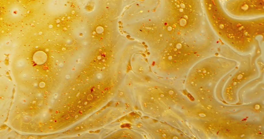 A light orange hued liquid bubbles as it flows and swirls