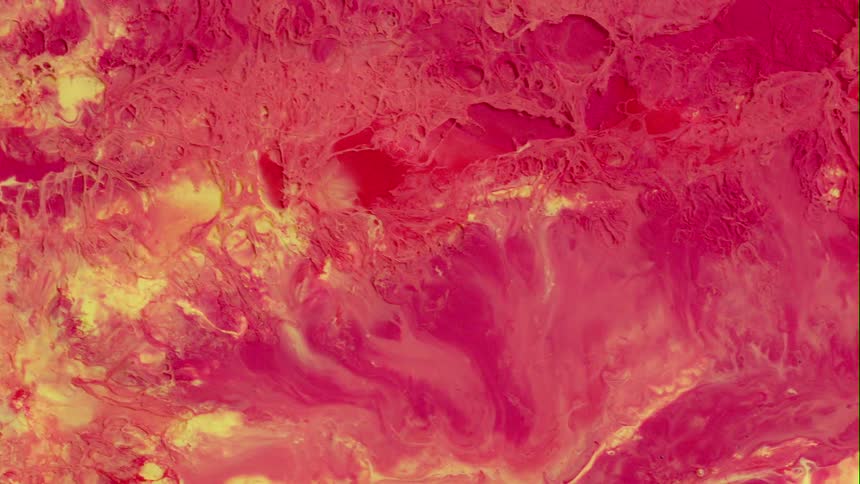 A bright red and yellow liquid substance blends together as it slowly moves