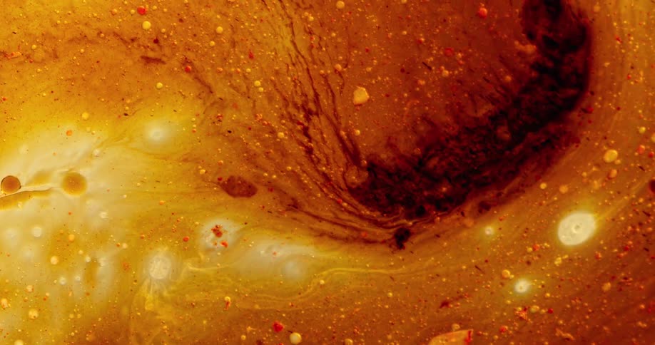 Orbs move in an organic yellow and orange substance as a darker color blends in as it moves