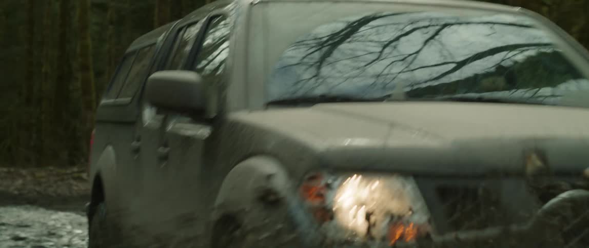 Black four wheel drive drives on muddy dirt road in the forest